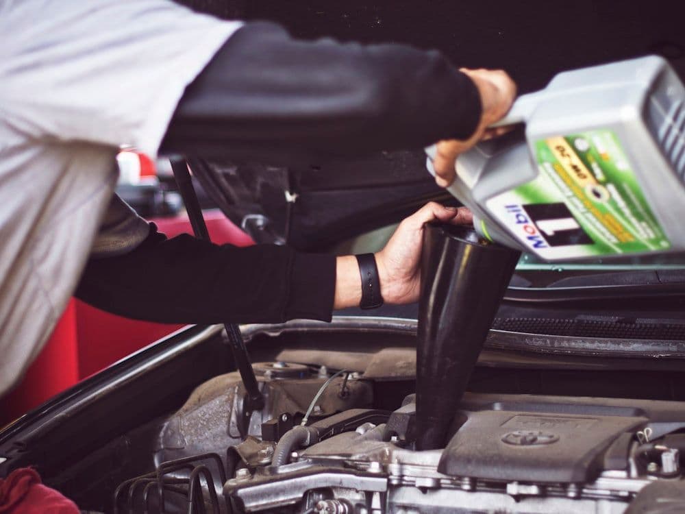 Mecânico trabalhando em um motor de carro com peças ao redor